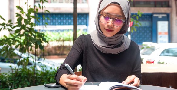 Muslim woman writing in a notebook