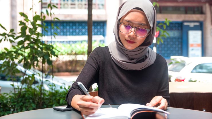 Muslim woman writing in a notebook